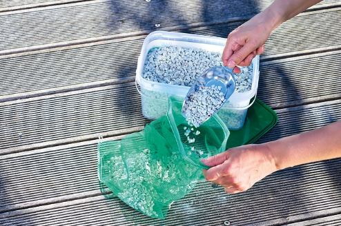 Befüllen eines Filterbeutels mit Oase AquaActiv PondLith 2,5 kg zur natürlichen Reduzierung von Nitrat und Nitrit im Gartenteich