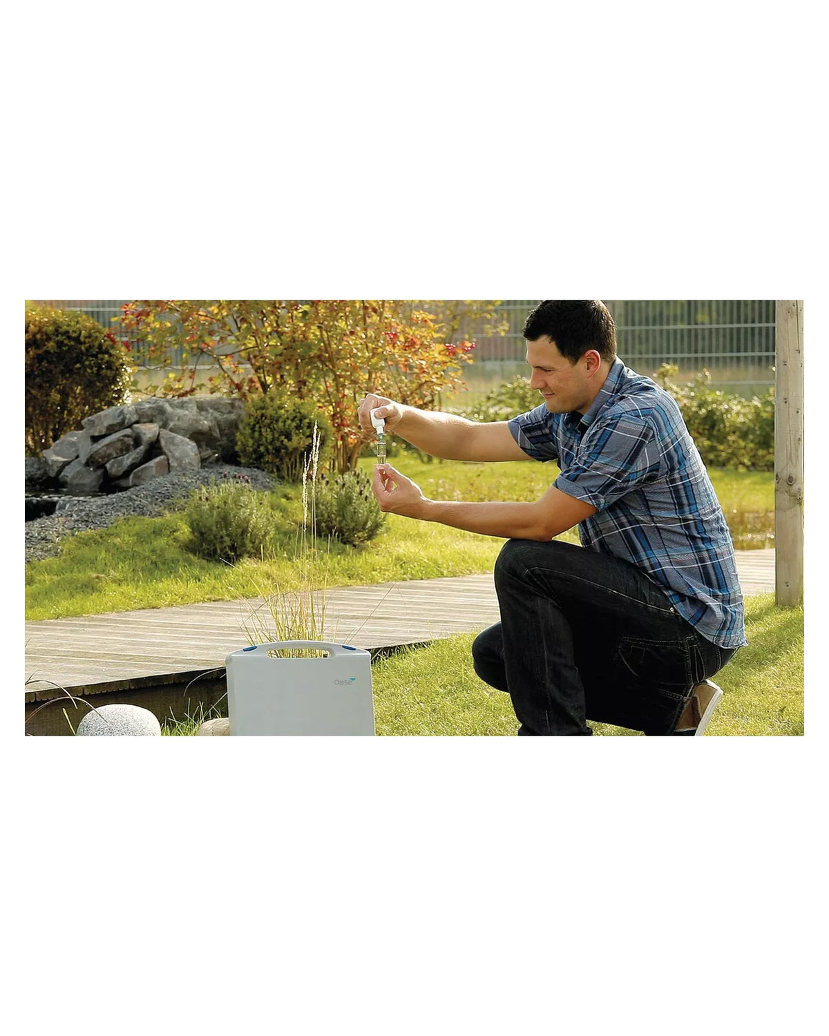 Mann prüft am Gartenteich eine Wasserprobe in der Glasampulle