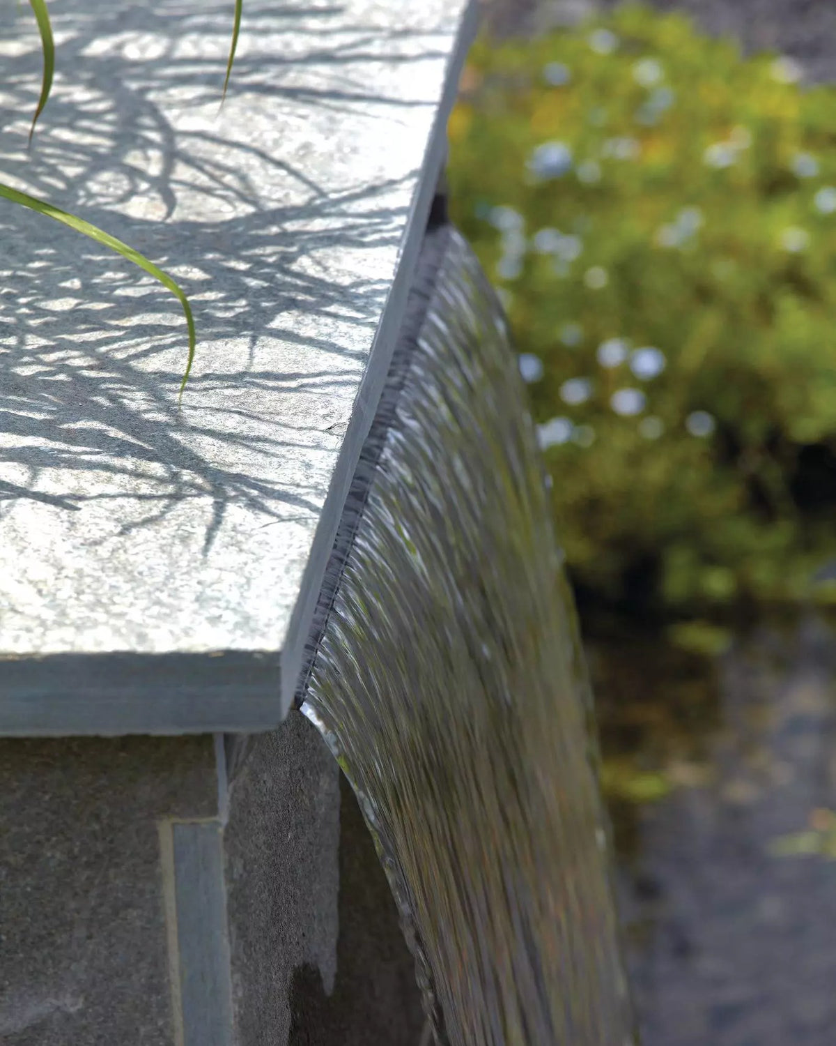 In eine Natursteinmauer eingebauter OASE Waterfall mit gleichmäßigem Wasserschleier