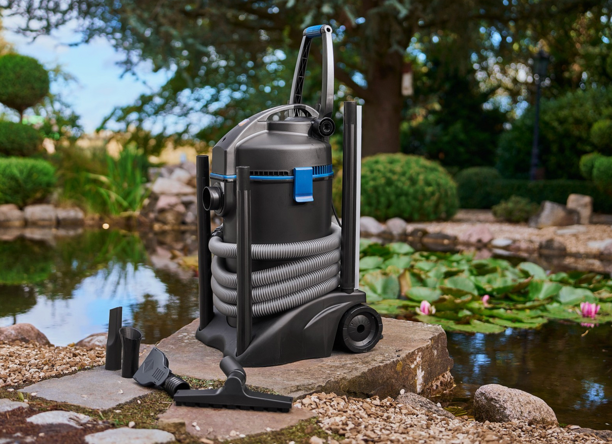 Teichsauger komplett mit Schlauch und Zubehör am Gartenteich neben Wasserpflanzen platziert Oace PondoVac3
