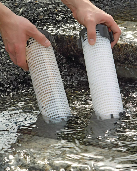 Zwei PhosLess-Filtersäulen werden in das fließende Wasser eines Bachlaufs gestellt