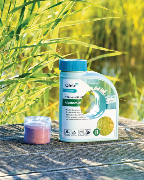 OASE PhosLess Direct 500-ml-Flasche und Messbecher mit Pulver auf einem Holzsteg am Teich
