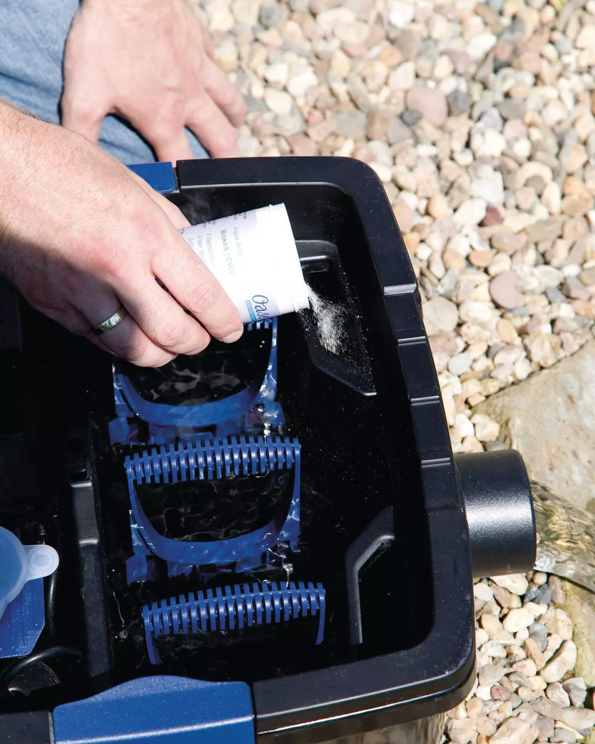 OASE FiltoMatic Set: Filterstarter wird in die geöffnete Filterkammer gegeben