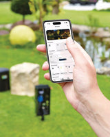OASE Control App mit Steckdosen, Dimmer und Geräten, dahinter der InScenio FM-Master Cloud im Garten