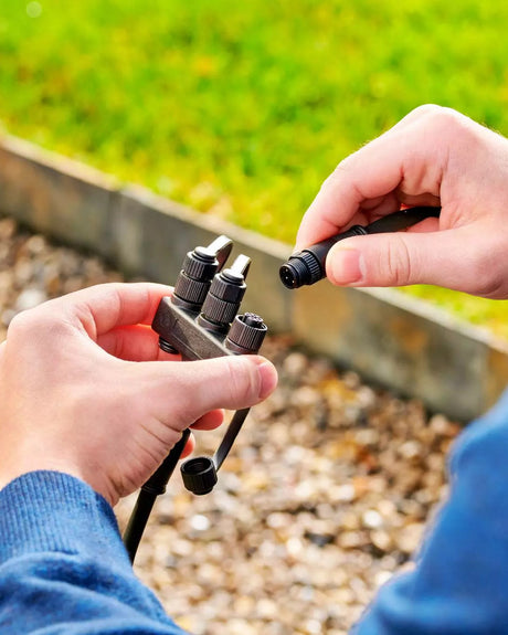 Ein Kabel wird an der Beetkante in den Dreifach-Verteiler RGB gesteckt
