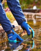 OASE Neopren-Teichhandschuhe mit OASE-Logo greifen am gemauerten Teichrand ins Wasser