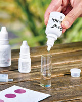 Tropflösung aus dem OASE Wasseranalyse Profi-Set wird in die Glasampulle mit der Wasserprobe gegeben