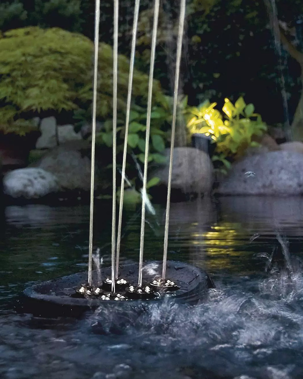 OASE Water Starlet in der Dämmerung mit fünf senkrechten Fontänen im Gartenteich