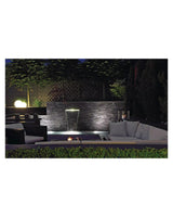 Terrasse mit Lounge-Möbeln und beleuchtetem Wandwasserfall am Abend